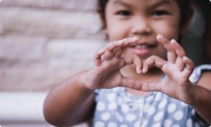 young girl making a heart with her hands