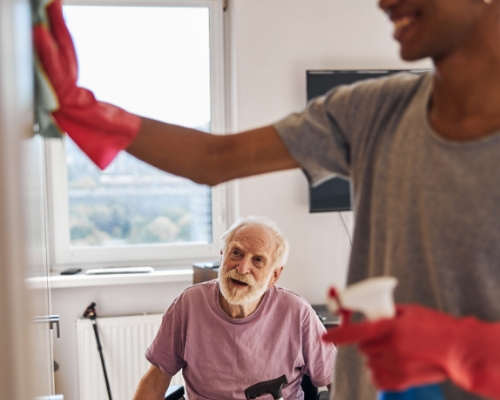 Caregiver helping clean elderly man's home